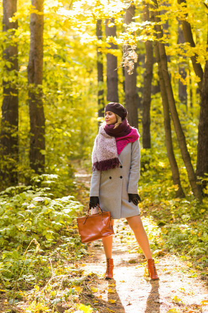 成人秋天 自然 人的概念-美丽的年轻女子在灰色外套和贝雷帽站太阳贝雷帽枫树