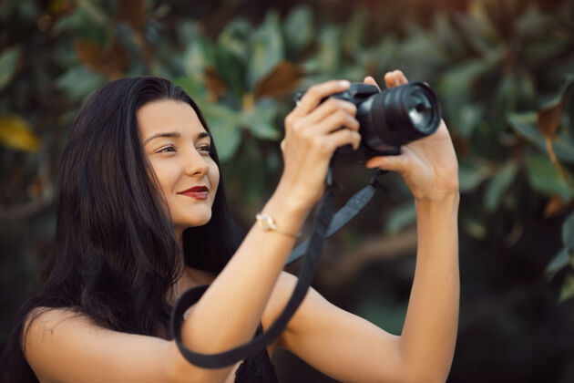 白种人在户外用单反相机拍照的迷人女摄影师朴槿惠快乐单反成人公园