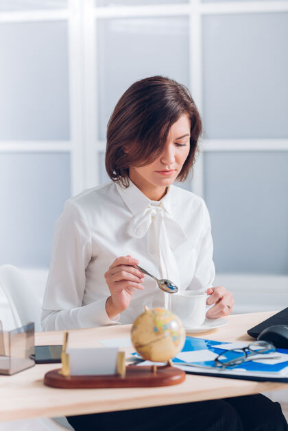 商务女性迷人的女商人在办公室喝咖啡 在办公桌旁工作坐着公司肖像