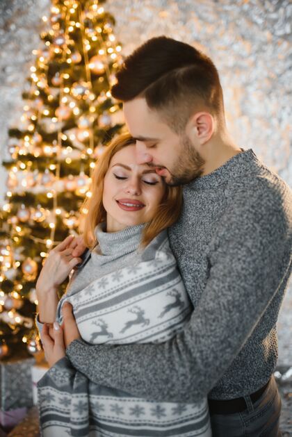 室内一对年轻夫妇在圣诞树前拥抱的照片浪漫帅哥拥抱