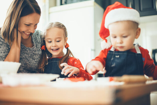 童年白种人的母亲和她的孩子穿着圣诞老人的衣服和烹饪食物准备圣诞节假期制作一起烹饪