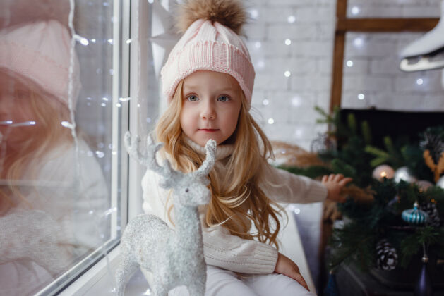 房子圣诞节早晨坐在窗台上的小女孩室内帽子欢呼