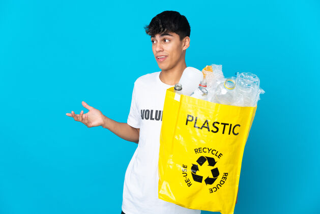 环境拿着一个装满塑料瓶的袋子在蓝色背景上循环 一边看一边惊讶的表情垃圾生态垃圾