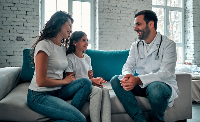 男性美国医生在和孩子和妈妈说话坐着女孩医疗