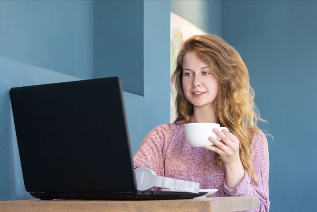 使用这个女孩为一家公司工作笔记本电脑.遥控器工作 在线女孩在咖啡馆里喝杯咖啡个人教程听