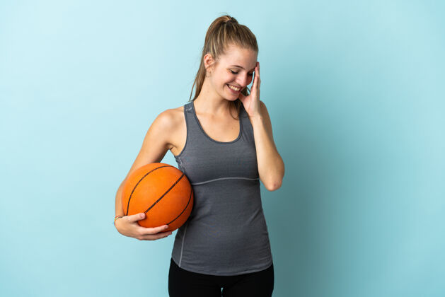 表情在蓝色背景上打篮球的年轻女子笑了好身体大笑
