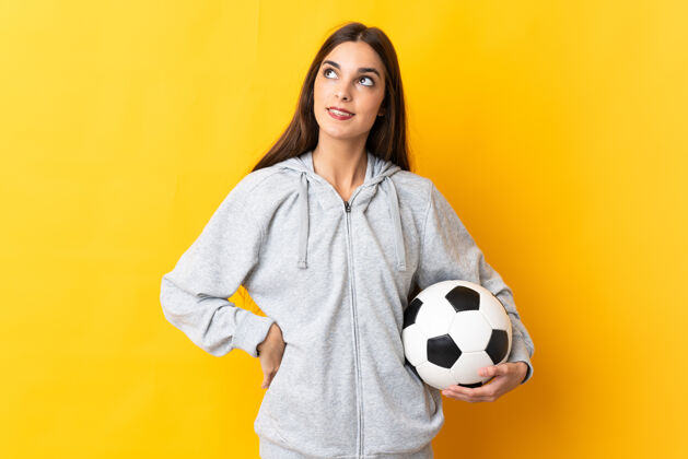 想象一个年轻的足球运动员 一个被隔离在黄色背景下的女人 一边抬头一边思考着一个想法女人想法黑发