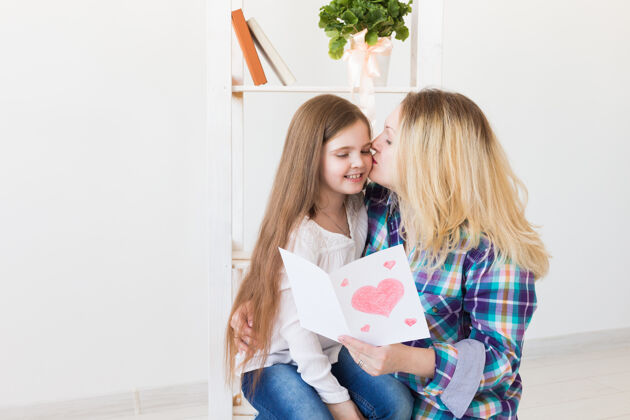 庆祝母亲节和家庭节日-母亲读女儿的贺卡惊喜女儿女性