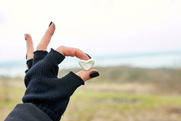 情人节一个戴着黑手套的旅行女孩手里拿着棉花糖 心里有型手套心户外