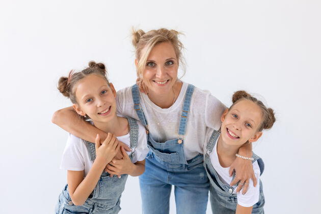 拥抱人 家庭和孩子的概念-双胞胎姐妹和他们的母亲在白色的表面亲子关系女士可爱