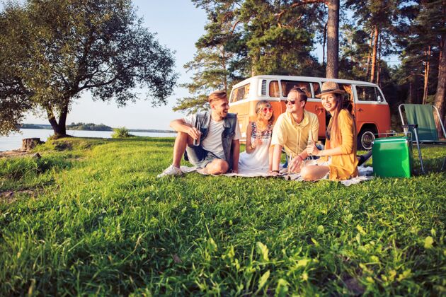 饮料在夏天的节日里 时髦的朋友们坐着露营车坐着朋友旅程