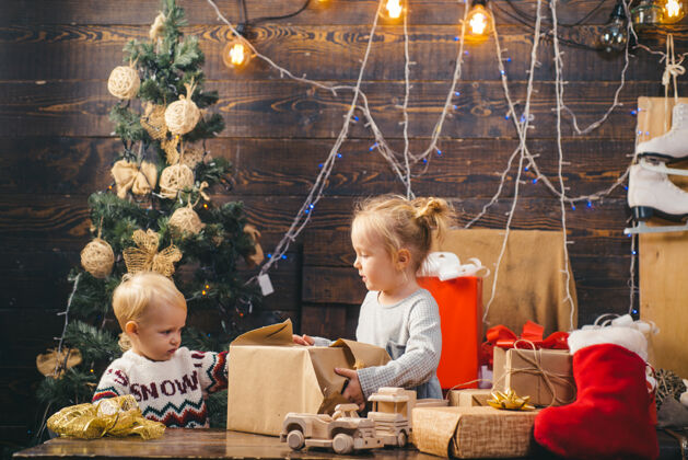 玩具可爱的小女孩正在装饰圣诞树室内圣诞节儿童肖像画快乐的孩子看着圣诞树旁装饰的玩具球有趣拥抱新