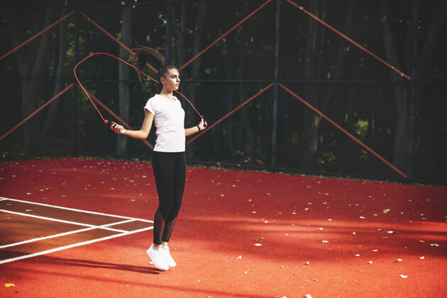 年轻一个年轻的女子早上在户外的运动公园里用跳绳跳绳健美生活方式动作