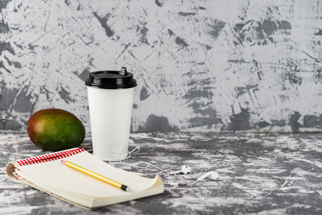 工作场所工作或教育去吧咖啡杯子 芒果 电话和一堆放在灰色石头上的记事本表.copy空间办公桌蛋糕手机