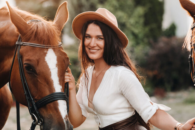 美丽一个戴帽子的女孩站在马旁边户外帽子农场