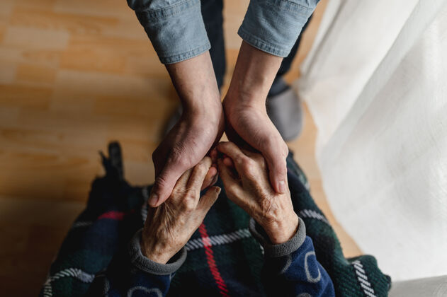 希望顶视图不可辨认的年轻人牵着老人的手老年妇女关怀 家庭观念爱世代连接