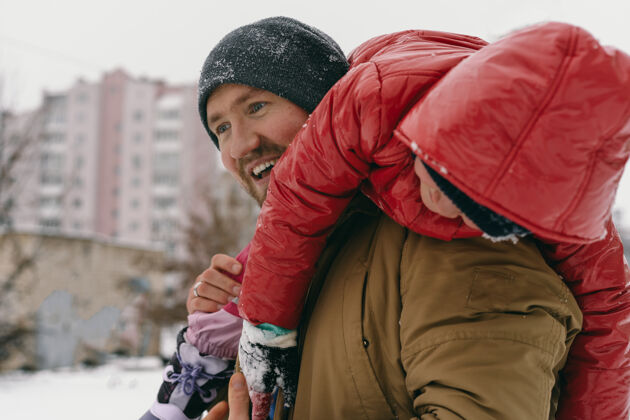 雪爸爸肩上抱着一个小女儿玩耍家庭孩子