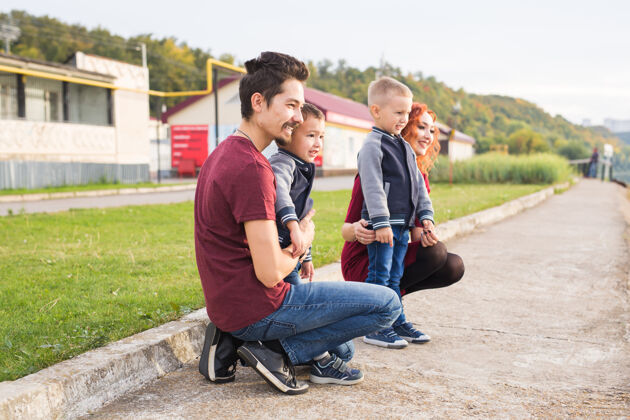 女人亲子关系 童年和家庭的概念-父母和两个男孩在公园散步和秋天爸爸父亲