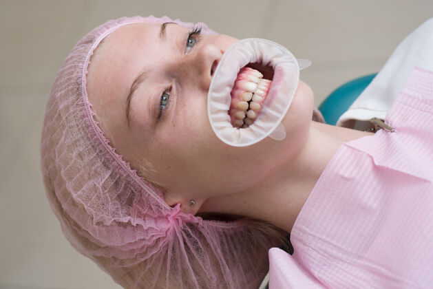 牙齿美丽的女孩坐在牙科手术椅上考试牙医高兴吗在模糊灯光下的抽象背景上微笑的女人嘴唇假形状