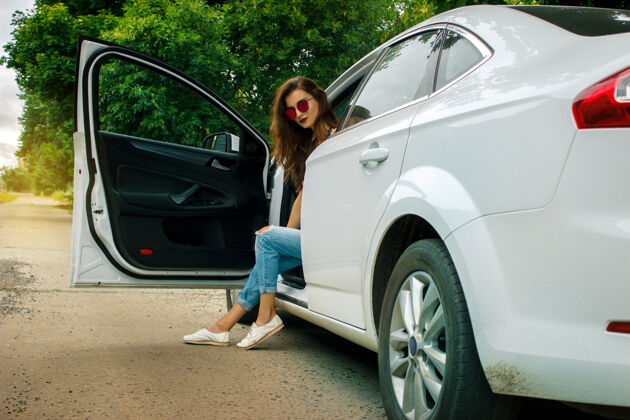 现代年轻迷人的戴眼镜的女士坐在一辆漂亮的白色大轿车里车辆昂贵女士