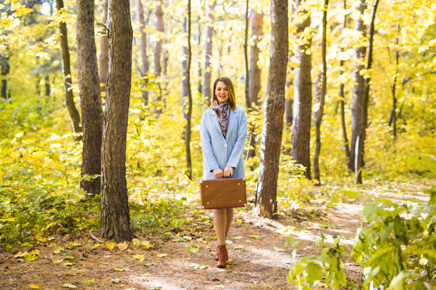 年轻人秋天 时尚 人的概念——女人带着棕色复古手提箱走过秋天的公园女人女孩公园