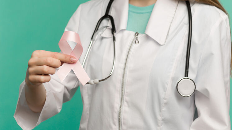心蓝色背景上的女医生手上的粉红丝带 用于乳腺癌的预防起来人护理