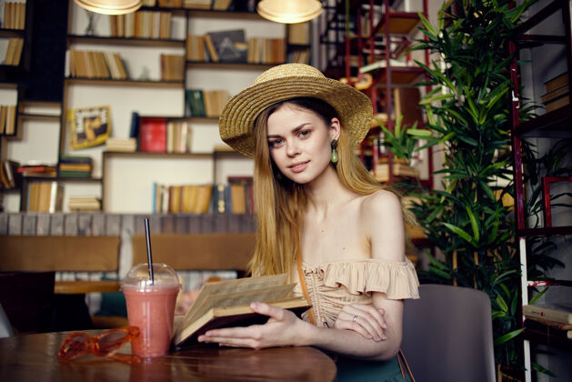 知识戴帽子的漂亮女人手里拿着书在咖啡馆看书度假学生学习桌子