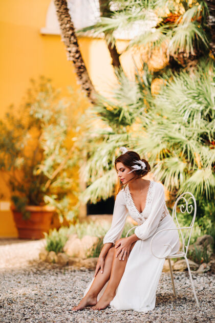 意大利婚礼一位美丽的新娘坐在一张椅子上 穿着内衣和晨衣微笑着 旁边是一座别墅意大利早上好托斯卡纳的新娘新娘头发别墅