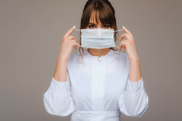冠状病毒一个女医生戴着医用面罩站在一个灰色的背景上信心医学女孩