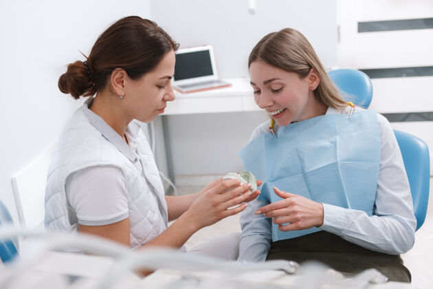 女性美丽的女人在检查完牙齿后高兴地和她的牙医交谈正确牙套保健