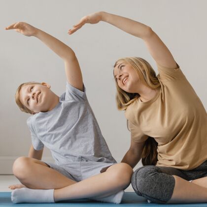 男孩女人和孩子一起锻炼练习垫子训练