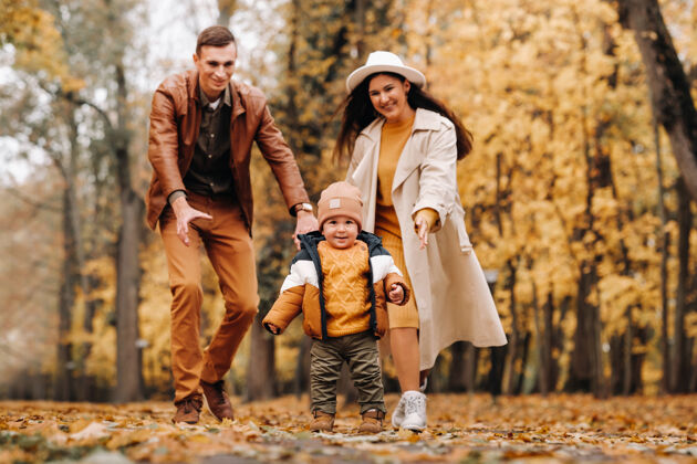童年爸爸和妈妈带着儿子在秋天的公园里散步树叶阳光年轻