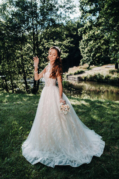 女人一个优雅的新娘在一个自然公园里穿着白色的裙子和一束花束的肖像优雅可爱浪漫