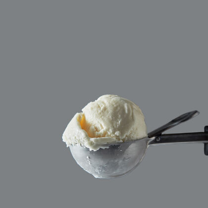 奶油特写美味的奶制品甜点冷白香草在一个金属勺冰淇淋上的灰色墙.夏季概念空间用于文本颜色风味牛奶