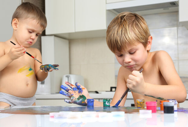 画家两个小男孩在一张白色的桌子上画画教育水孩子