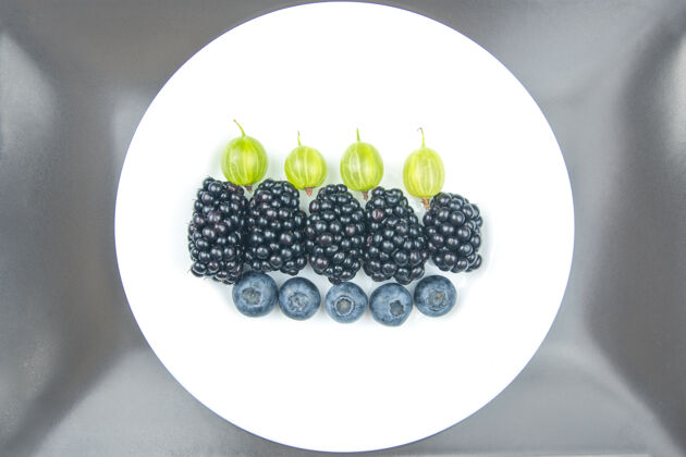 集浆果蓝莓 醋栗和黑莓放在白色盘子里新鲜有机甜点