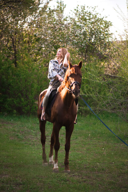 青少年在阳光明媚的草地上 一位留着长发的年轻女子和一匹棕色的马在森林里合影动物美丽青少年