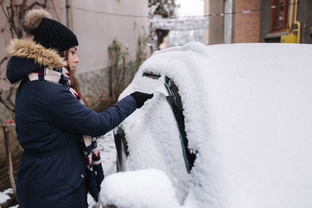 汽车一个女人正在用刮雪机擦车窗上的积雪户外女士冷冻
