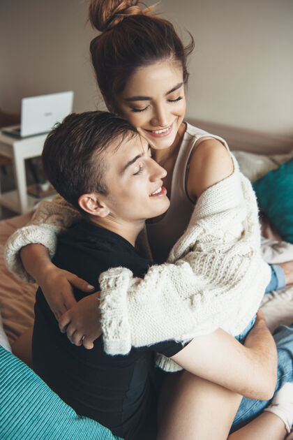 男人幸福的高加索夫妇躺在床上微笑着拥抱对方床房子女孩
