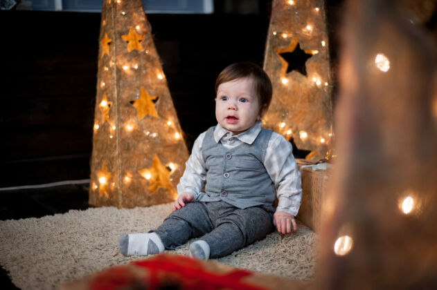 脸小男孩坐在家里的圣诞树旁礼物有趣肖像