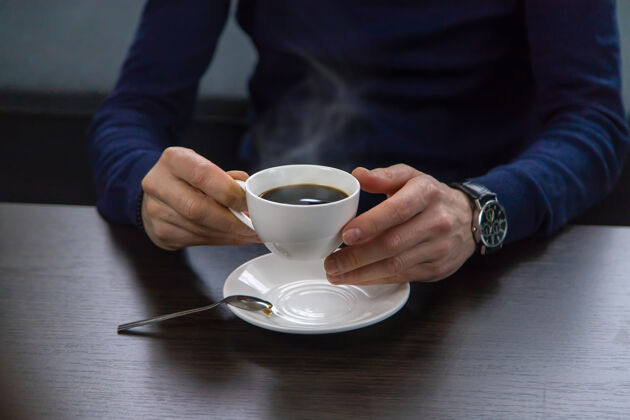 拿铁一个男人端着一杯咖啡坐在桌边坐着会议手