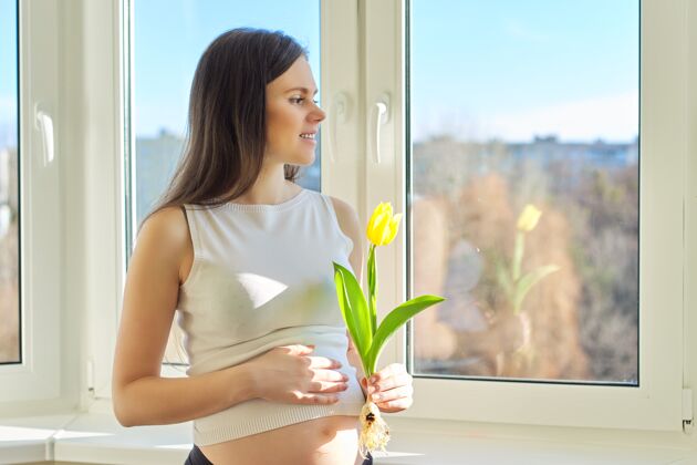 女孩春天 美丽 健康 年轻孕妇的画像与黄色郁金香在家附近窗户很漂亮女性拥有健康的皮肤和头发 自然的妆容 复制空间芳香美丽健康