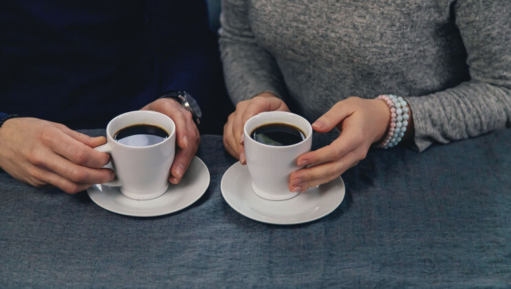 会议一男一女端着一杯咖啡坐在桌边交谈咖啡心