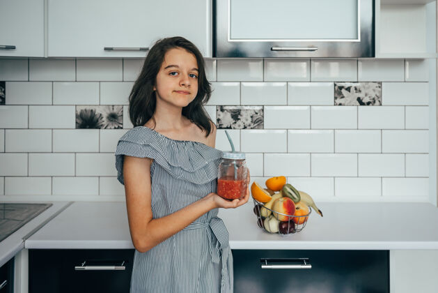 女性快乐的年轻家庭主妇 在现代化的厨房里享用水果健康女孩厨房