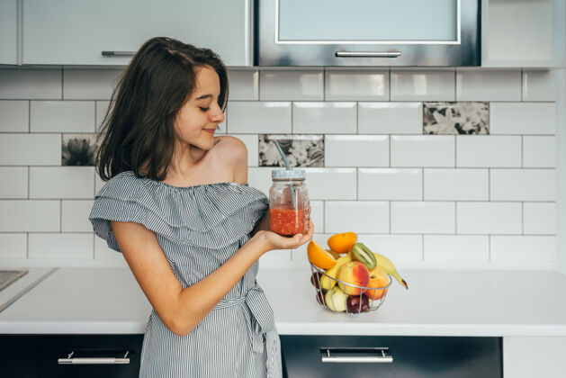 女性快乐的年轻家庭主妇 在现代化的厨房里享用水果自然现代人