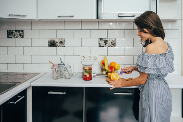 健康快乐的少女在厨房的搅拌机里做新鲜的果汁或饭菜有机护理厨房
