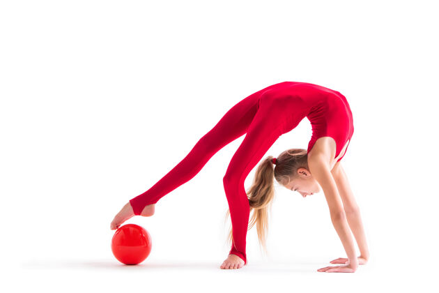 训练穿着红色连体衣的体操女孩在白色背景上拿着球做运动身体表演年轻