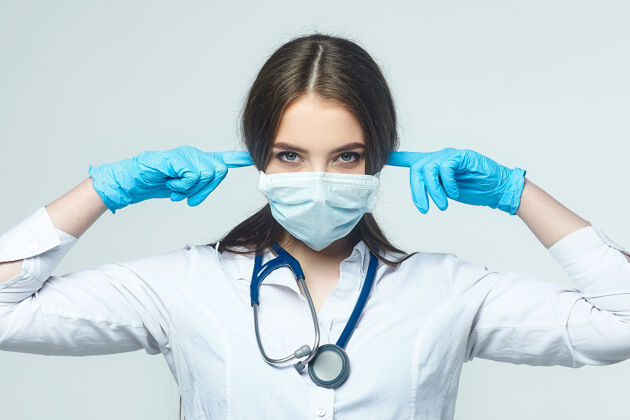 病毒年轻的女医生用手捂住耳朵留在家里实习生医学
