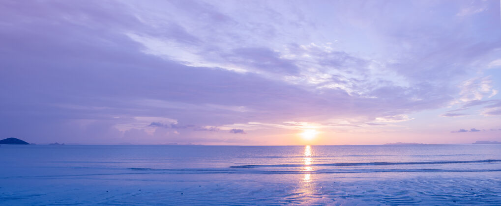 海景美丽的热带紫蓝色海洋日落和黄云背景全景反射夜晚粉彩