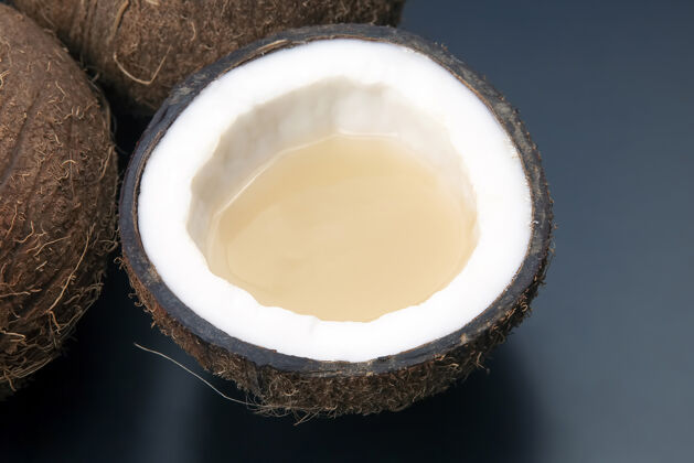 新鲜切新鲜椰子与真正的椰子奶在黑暗中背景.维生素水果健康食物甜味一半饮食